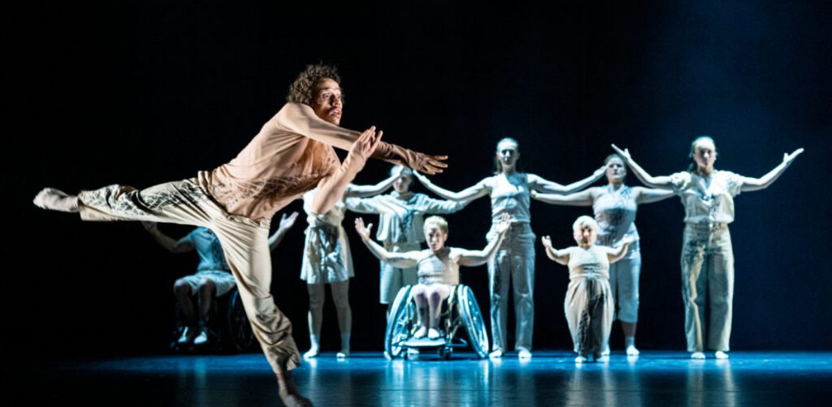 A group of dancers including 2 in a wheelchair performs a synchronized routine under dramatic lighting with one dancer in foreground. Image by Lars Opstad from Europe Beyond Access.