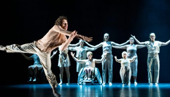 A group of dancers including 2 in a wheelchair performs a synchronized routine under dramatic lighting with one dancer in foreground. Image by Lars Opstad from Europe Beyond Access.