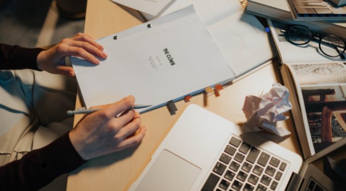 Person at a desk with a script and laptop