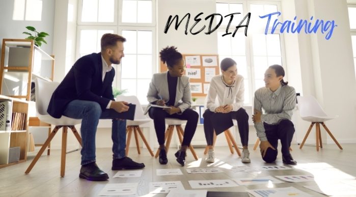 Caption MEDIA Training. Background image of 3 women and a man in a bright office space looking at documents on the floor.